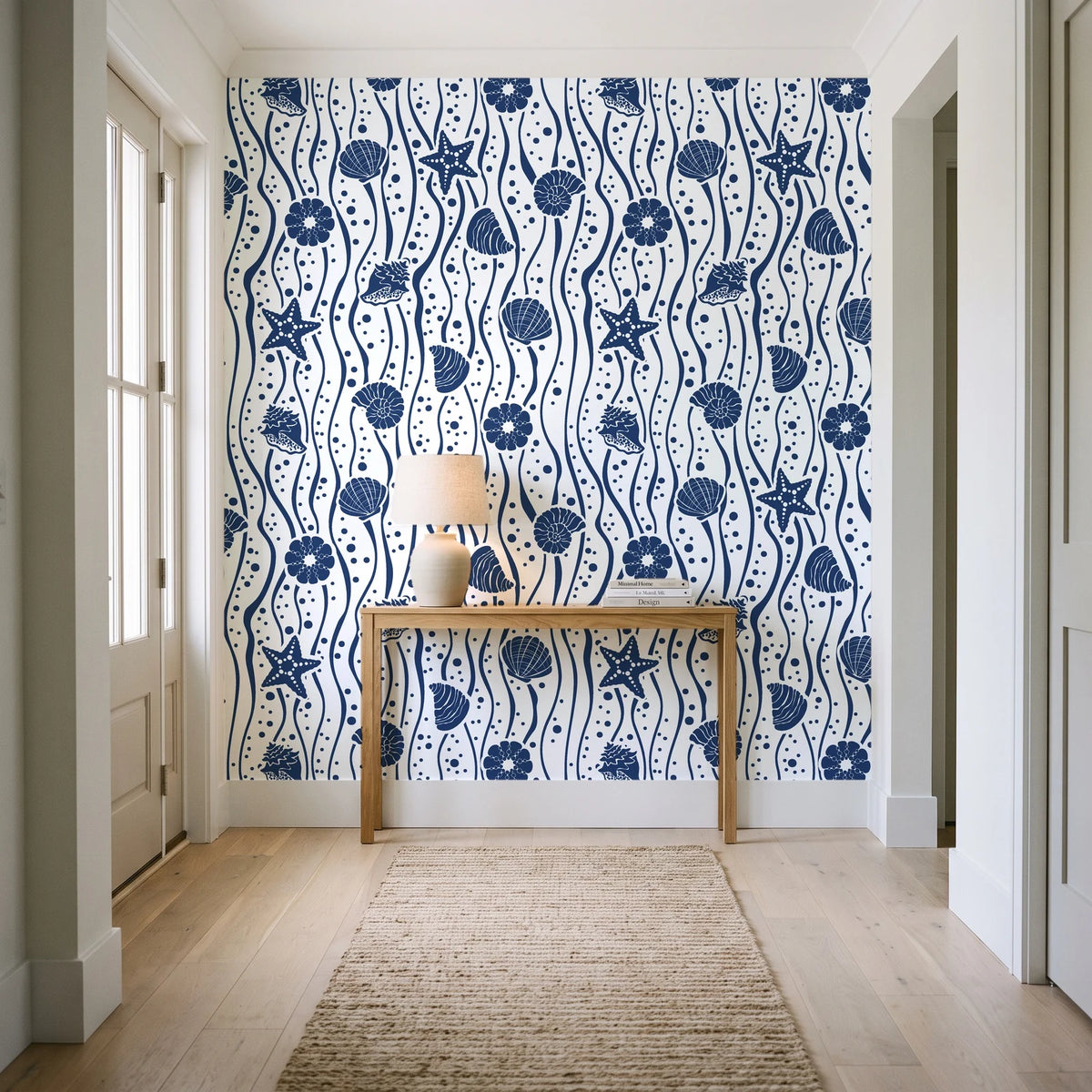 Apricot Tides Navy coastal seashell wallpaper behind a console table in a light entry hallway
