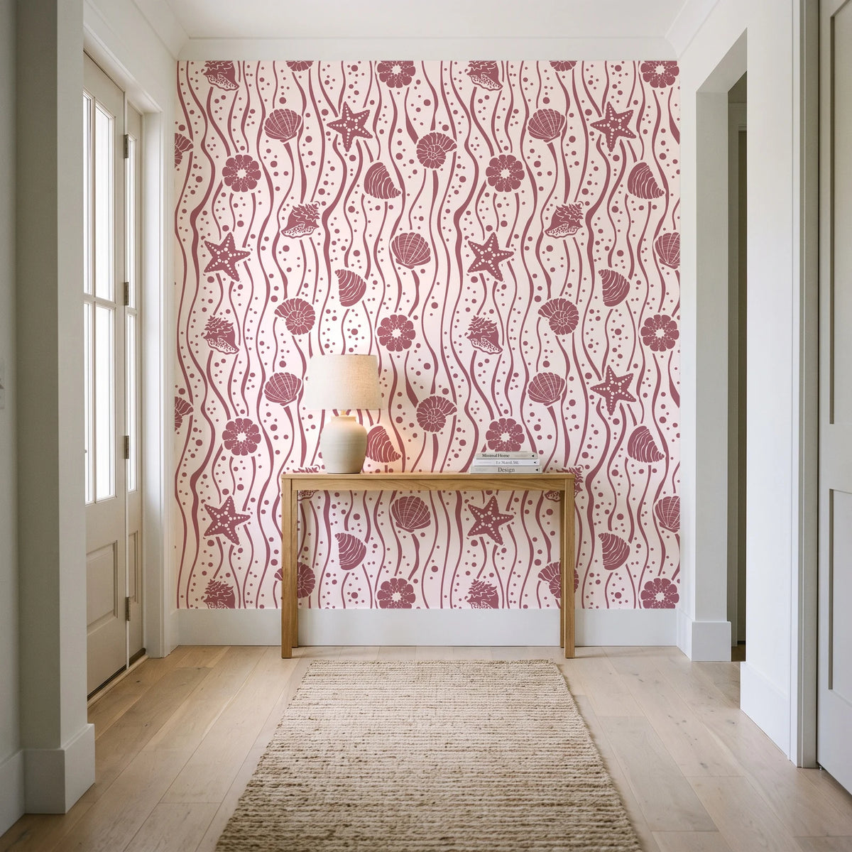 Apricot Tides Rosewood coastal seashell wallpaper behind a console table in a light entry hallway