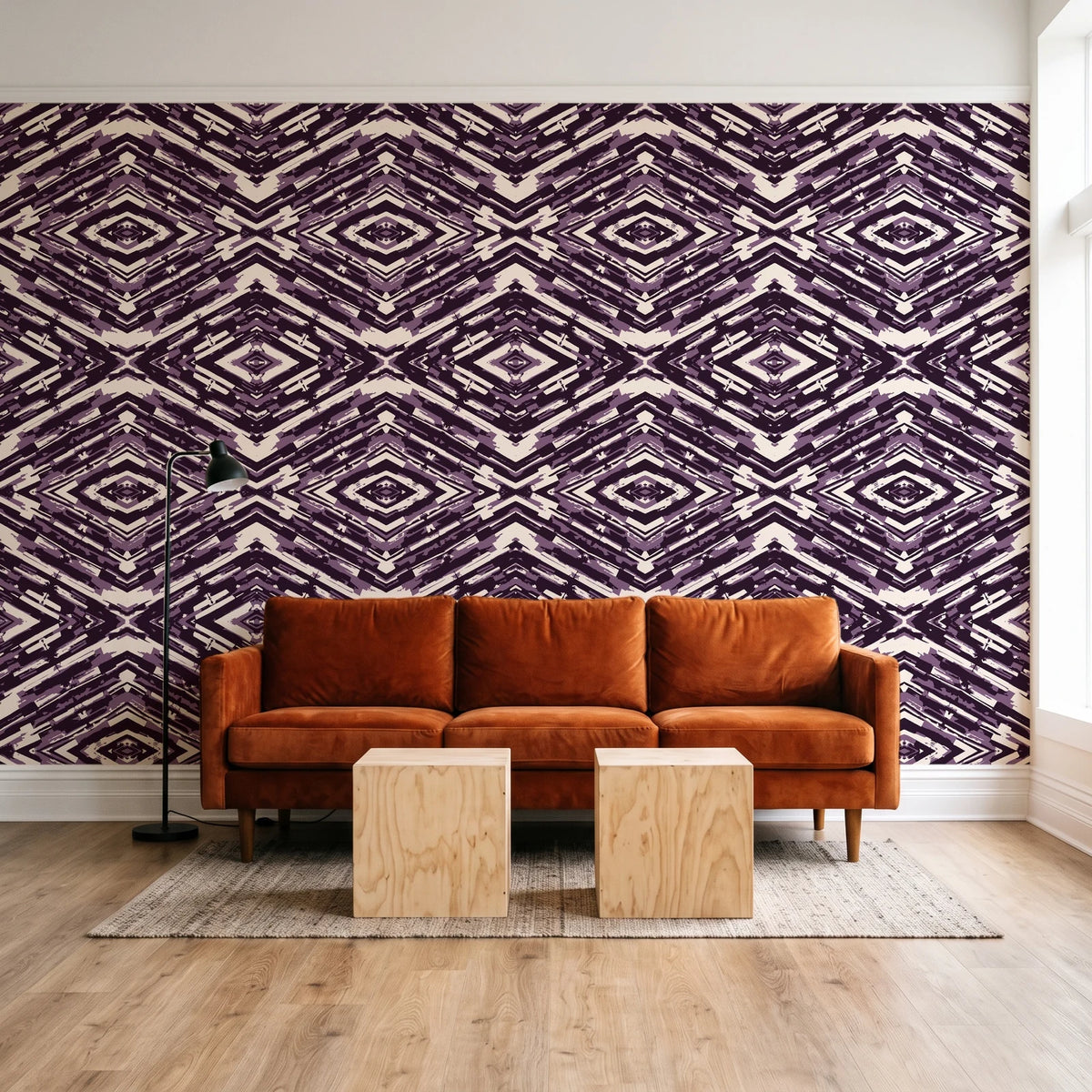 Arrows At Dawn Aubergine geometric diamond wallpaper behind a rust velvet sofa in a bright coworking lounge
