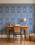 Aztec Quilt Indigo geometric tribal wallpaper behind a vintage writing desk in a cozy craft-room home office