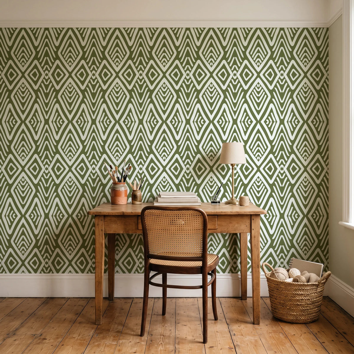 Aztec Quilt Olive geometric tribal wallpaper behind a vintage writing desk in a cozy craft-room home office