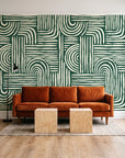 Bantu Lines Emerald brush geometric wallpaper behind a rust velvet sofa in a bright coworking lounge