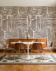 Bantu Lines Espresso brush geometric wallpaper in a mid-century dining room with a teak sideboard and tulip table