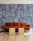 Bantu Lines Navy brush geometric wallpaper behind a rust velvet sofa in a bright coworking lounge
