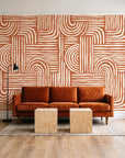 Bantu Lines Terracotta brush geometric wallpaper behind a rust velvet sofa in a bright coworking lounge