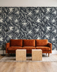 Blueprint Bloom Charcoal floral line wallpaper behind a rust velvet sofa in a bright coworking lounge