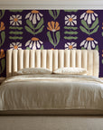 Bohemian Daisy Aubergine retro floral wallpaper behind a channel-tufted bed in a calm primary bedroom