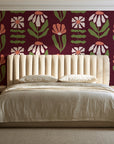 Bohemian Daisy Oxblood retro floral wallpaper behind a channel-tufted bed in a calm primary bedroom