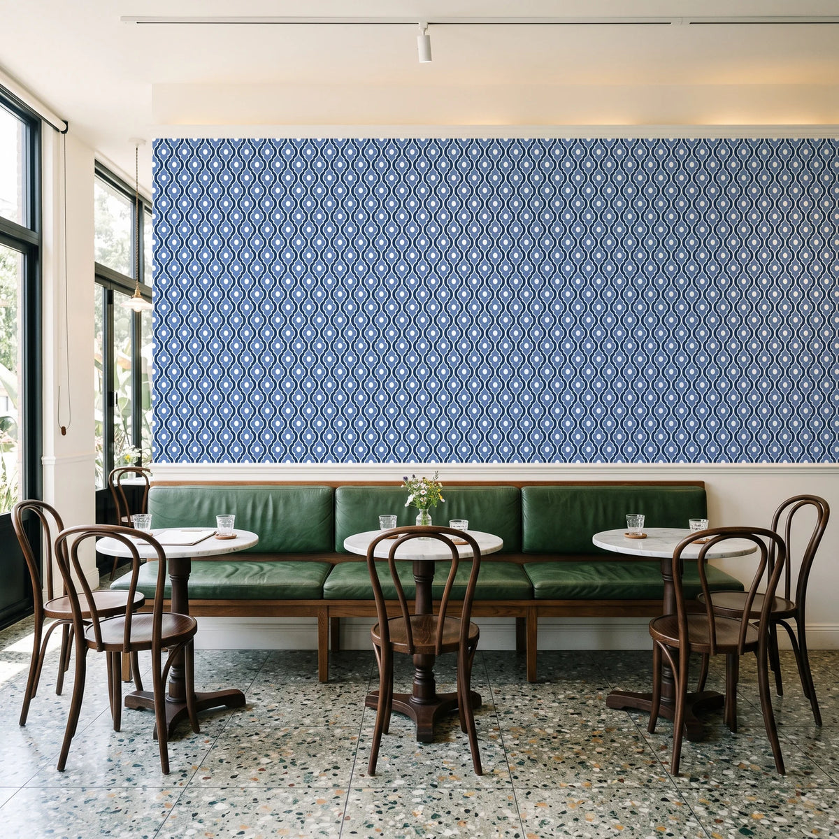 Butter Ogee Midnight ogee trellis wallpaper above a green leather banquette in a sunlit neighborhood cafe