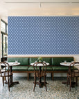 Butter Ogee Midnight ogee trellis wallpaper above a green leather banquette in a sunlit neighborhood cafe