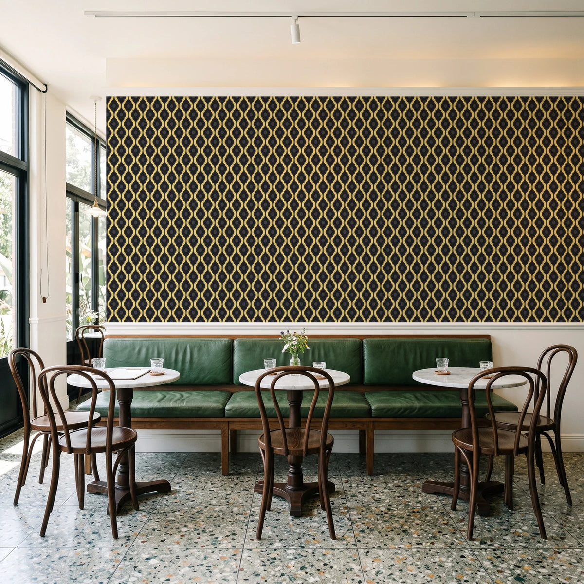 Butter Ogee Noir ogee trellis wallpaper above a green leather banquette in a sunlit neighborhood cafe