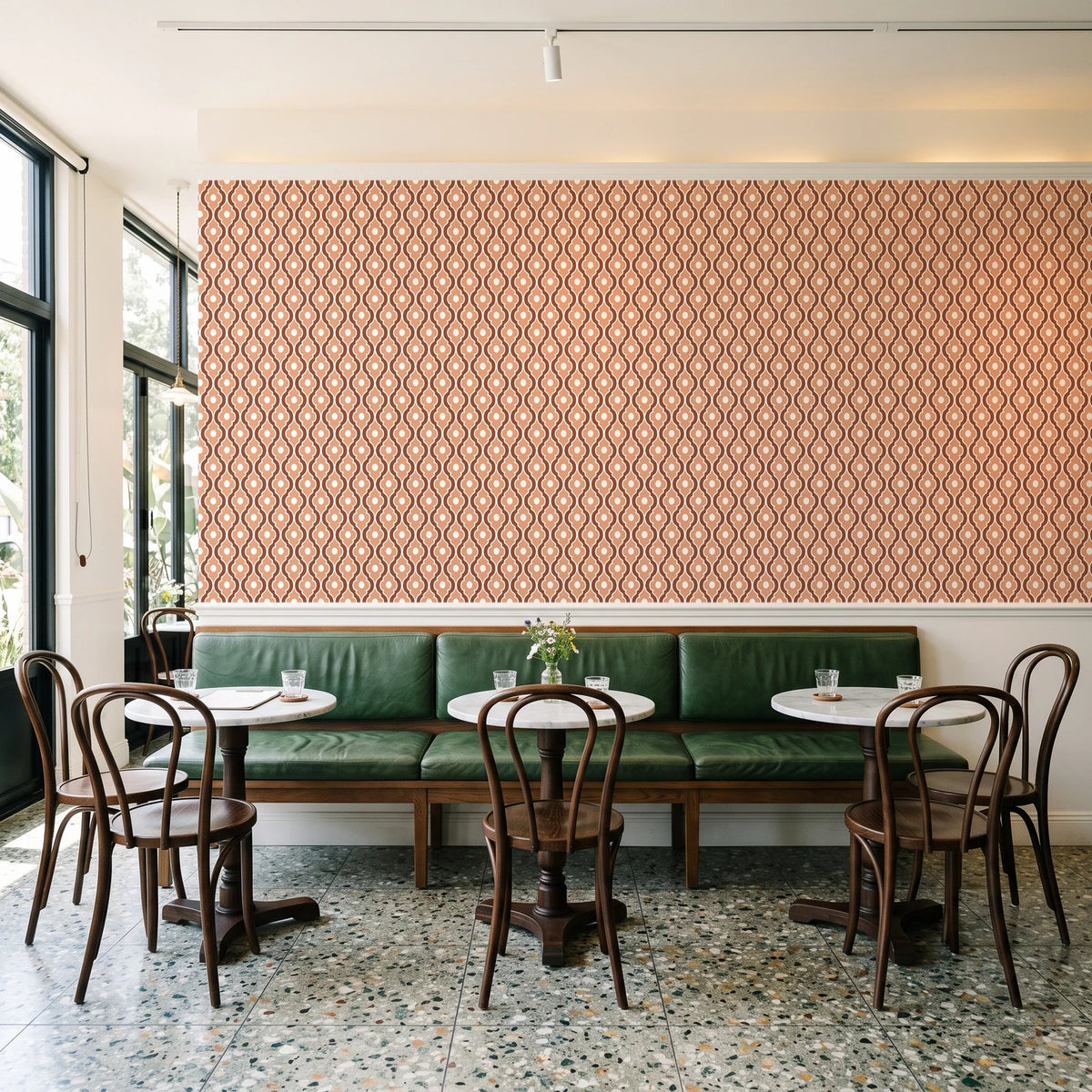 Butter Ogee Terracotta ogee trellis wallpaper above a green leather banquette in a sunlit neighborhood cafe