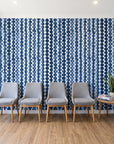 Cactus Lane Navy abstract stripe wallpaper behind a row of upholstered chairs in a bright clinic waiting room