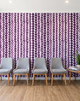 Cactus Lane Plum abstract stripe wallpaper behind a row of upholstered chairs in a bright clinic waiting room