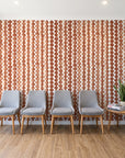 Cactus Lane Terracotta abstract stripe wallpaper behind a row of upholstered chairs in a bright clinic waiting room