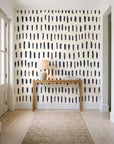 Canvas Dash Charcoal minimalist dashes wallpaper behind a console table in a light entry hallway