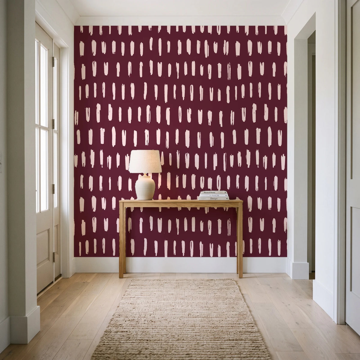 Canvas Dash Oxblood minimalist dashes wallpaper behind a console table in a light entry hallway