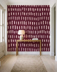 Canvas Dash Oxblood minimalist dashes wallpaper behind a console table in a light entry hallway