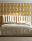 Canyon Ikat Ochre geometric wallpaper behind a channel-tufted bed in a calm primary bedroom