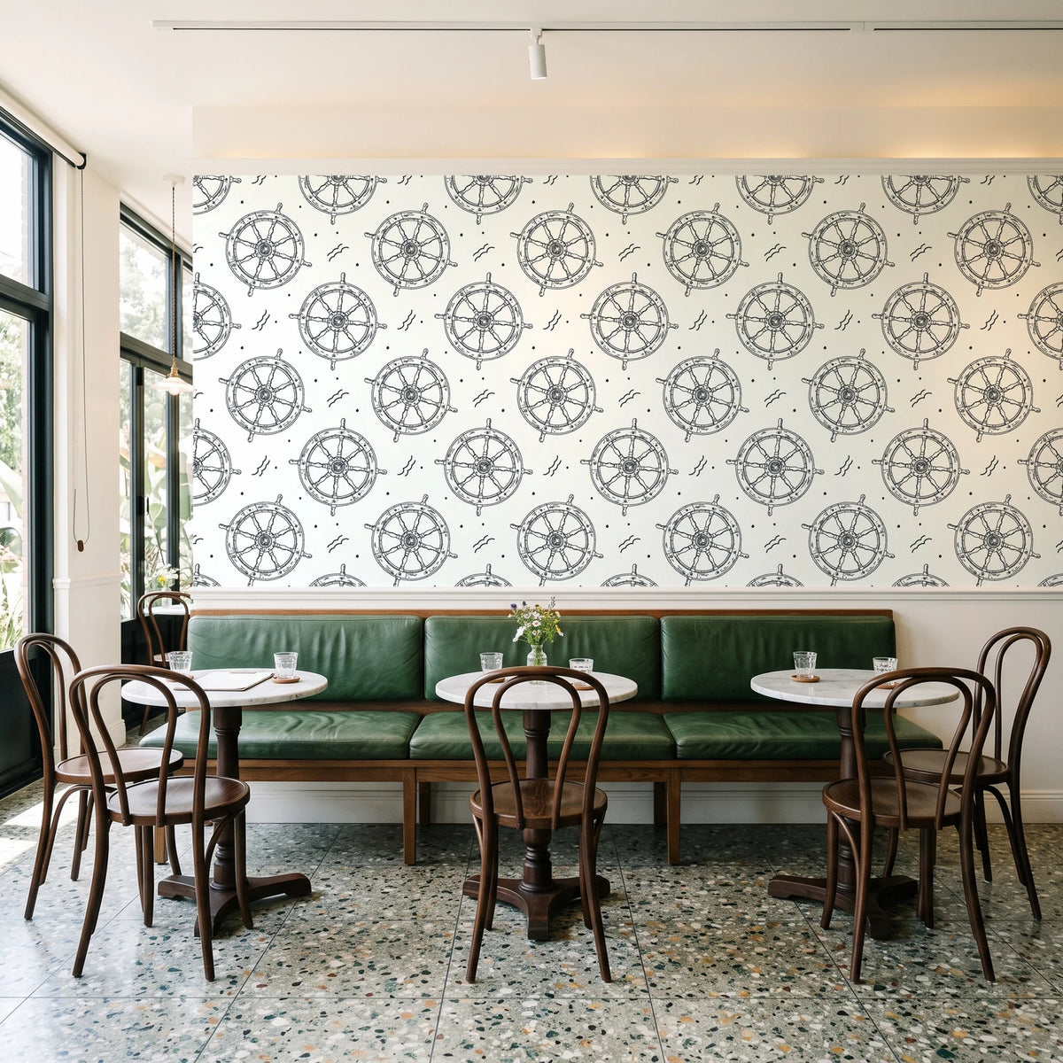 Captain's Wheel Charcoal nautical ship wheel wallpaper above a green leather banquette in a sunlit neighborhood cafe