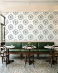 Captain's Wheel Charcoal nautical ship wheel wallpaper above a green leather banquette in a sunlit neighborhood cafe