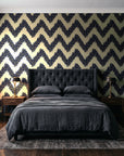 Caramel Drip Midnight chevron wallpaper behind a tufted headboard in a dark, moody bedroom