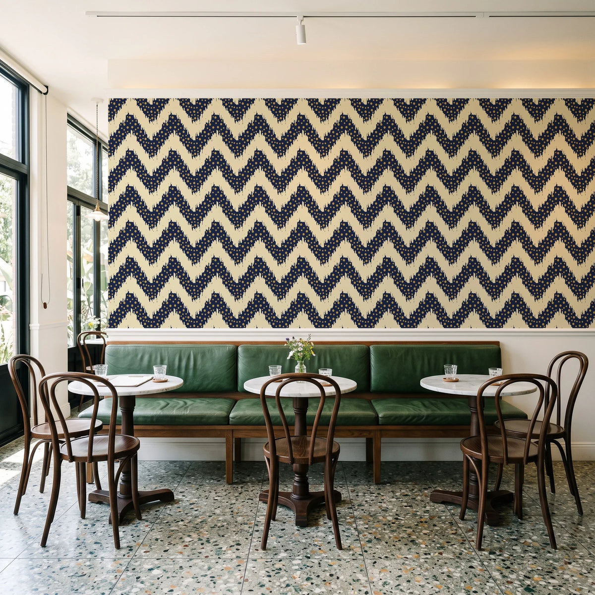 Caramel Drip Midnight chevron wallpaper above a green leather banquette in a sunlit neighborhood cafe