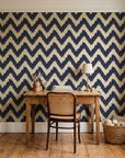 Caramel Drip Midnight chevron wallpaper behind a vintage writing desk in a cozy craft-room home office