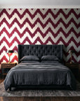 Caramel Drip Oxblood chevron wallpaper behind a tufted headboard in a dark, moody bedroom
