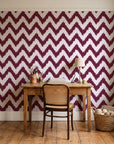 Caramel Drip Oxblood chevron wallpaper behind a vintage writing desk in a cozy craft-room home office