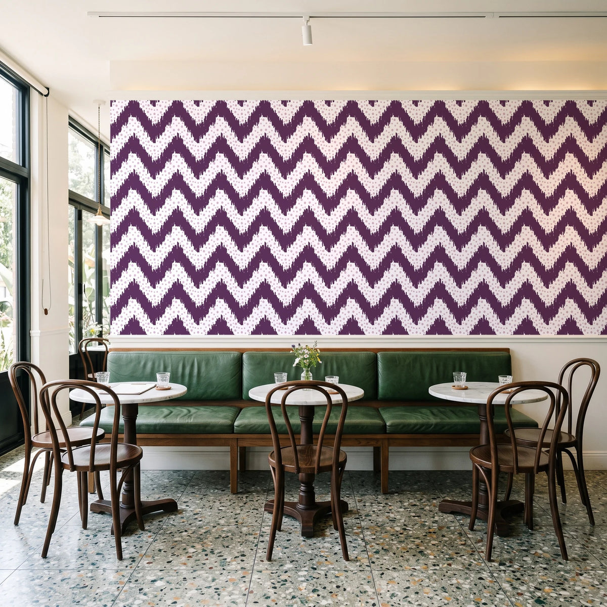 Caramel Drip Plum chevron wallpaper above a green leather banquette in a sunlit neighborhood cafe