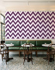 Caramel Drip Plum chevron wallpaper above a green leather banquette in a sunlit neighborhood cafe