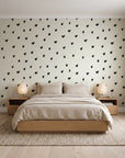 Caramel Haze Ivory brushstroke dot wallpaper behind a low platform bed in a serene Japandi bedroom