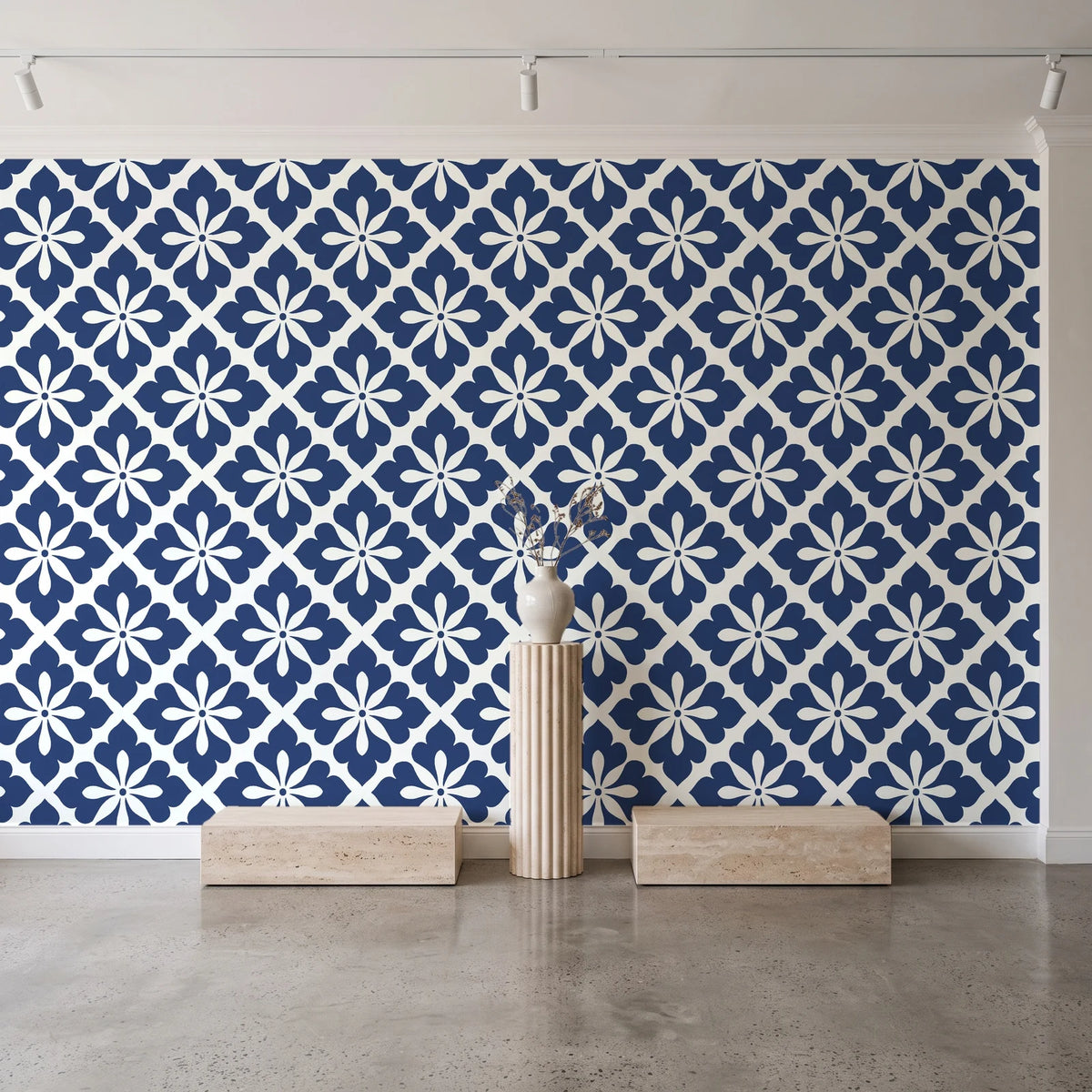 Carbon Bloom Navy tile floral wallpaper behind a travertine pedestal and vase in a minimal boutique