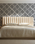 Chevron Etch Ebony geometric diamond wallpaper behind a channel-tufted bed in a calm primary bedroom