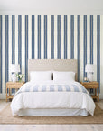 Citrine Column Navy stripe wallpaper behind a queen bed in a bright coastal bedroom