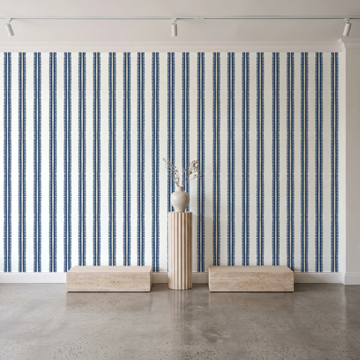 Citrine Column Navy stripe wallpaper behind a travertine pedestal and vase in a minimal boutique