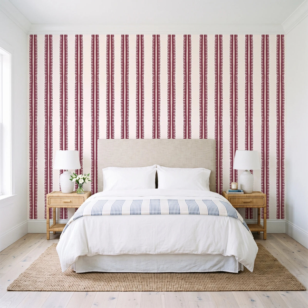 Citrine Column Oxblood stripe wallpaper behind a queen bed in a bright coastal bedroom