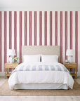 Citrine Column Oxblood stripe wallpaper behind a queen bed in a bright coastal bedroom