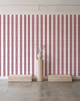 Citrine Column Oxblood stripe wallpaper behind a travertine pedestal and vase in a minimal boutique
