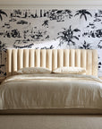 Coastal Village Charcoal palm toile wallpaper behind a channel-tufted bed in a calm primary bedroom