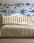 Coastal Village Navy palm toile wallpaper behind a channel-tufted bed in a calm primary bedroom