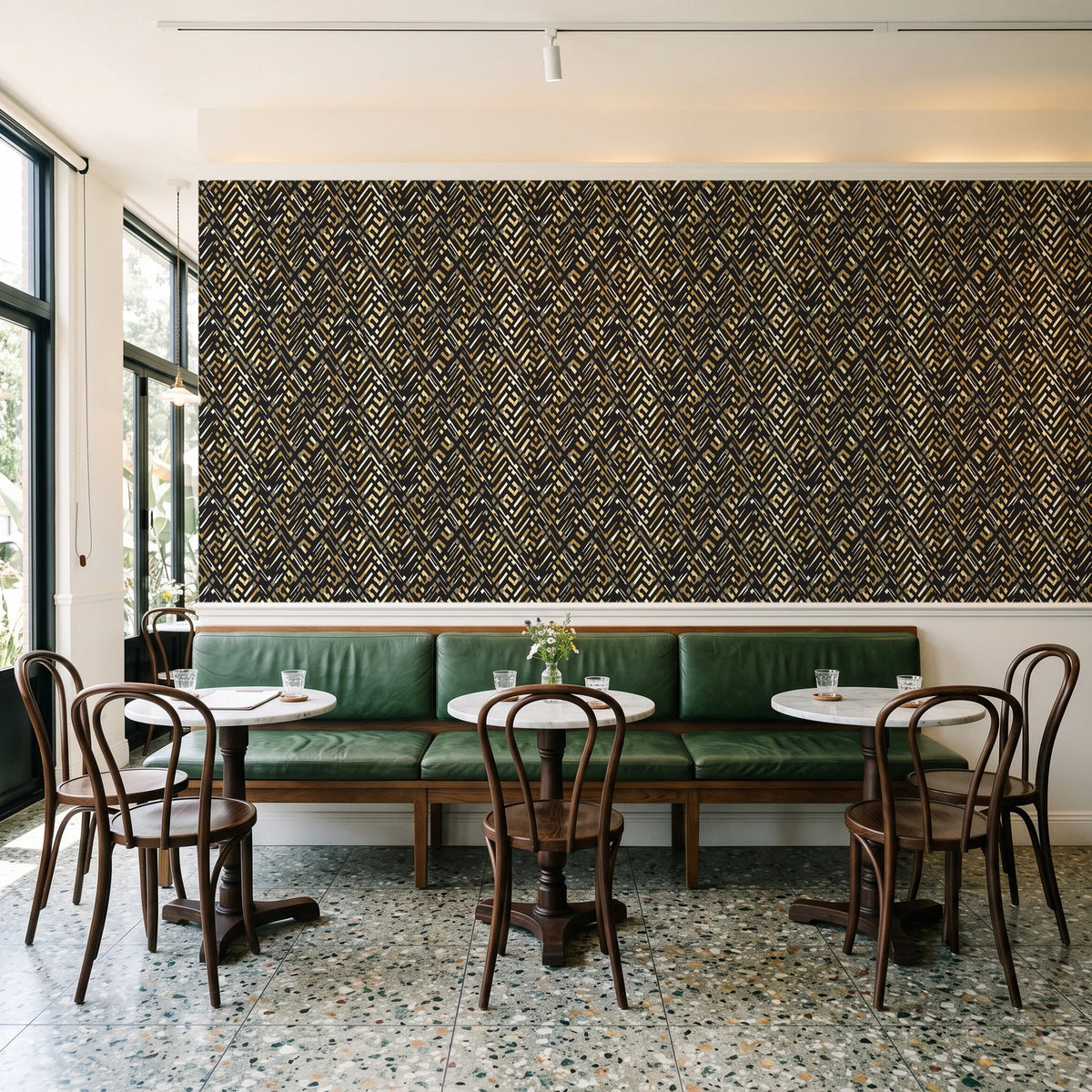 Crossroads Noir geometric wallpaper above a green leather banquette in a sunlit neighborhood cafe