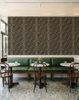 Crossroads Noir geometric wallpaper above a green leather banquette in a sunlit neighborhood cafe