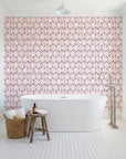 Crossroads Plum geometric wallpaper behind a freestanding tub in a bright coastal bathroom