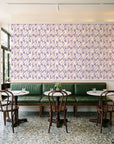 Crossroads Plum geometric wallpaper above a green leather banquette in a sunlit neighborhood cafe