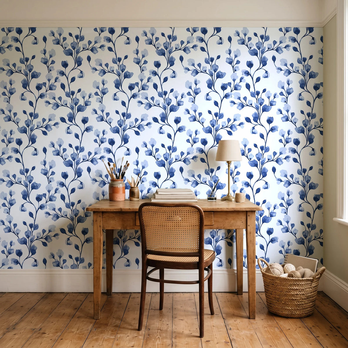 Desert Bloom Indigo botanical vine wallpaper behind a vintage writing desk in a cozy craft-room home office