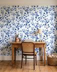 Desert Bloom Indigo botanical vine wallpaper behind a vintage writing desk in a cozy craft-room home office