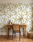 Desert Bloom Ochre botanical vine wallpaper behind a vintage writing desk in a cozy craft-room home office