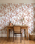 Desert Bloom Terracotta botanical vine wallpaper behind a vintage writing desk in a cozy craft-room home office